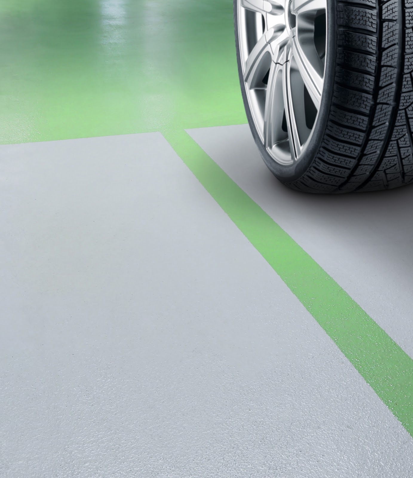 Beschichteter Industrieboden in Grau mit grüner Markierung und einem Autoreifen.