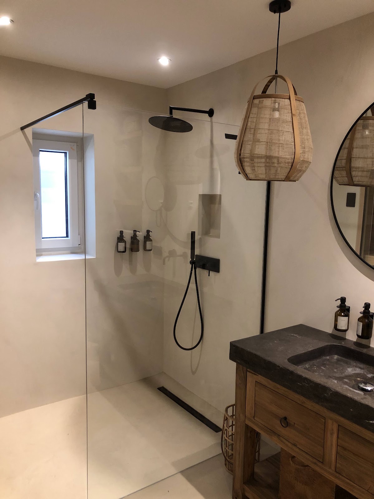 Modernes Badezimmer mit bodengleicher Dusche und hellen Wänden in fugenloser Spachteloptik.
